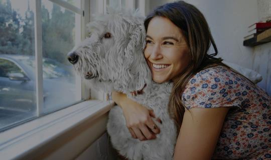 Female hugging dog looking out of window