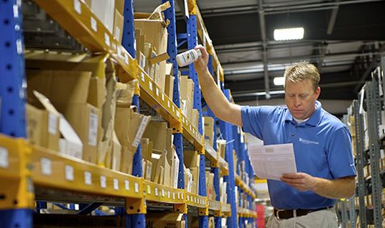 MWI Animal Health employee in blue shirt pulling a product in a warehouse